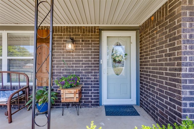 entrance to property featuring covered porch and brick siding