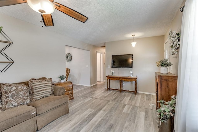 living room with baseboards, a ceiling fan, wood finished floors, and a textured ceiling