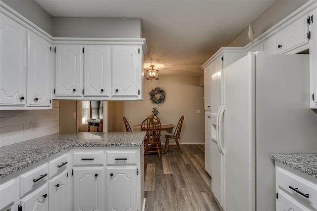 kitchen with white cabinets, backsplash, a peninsula, light wood-style flooring, and white refrigerator with ice dispenser