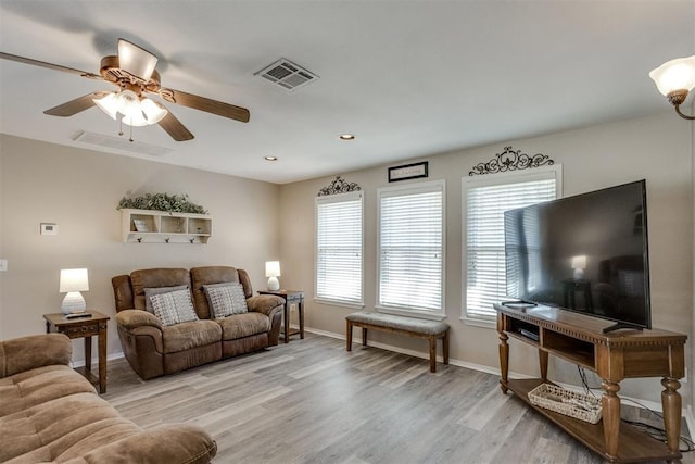 living area with baseboards, a ceiling fan, visible vents, and light wood-style flooring