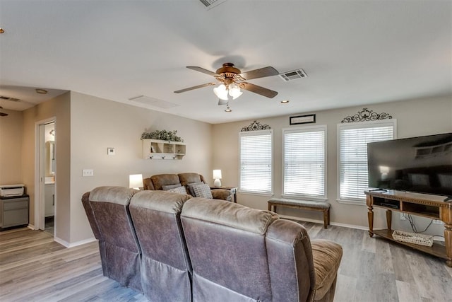 living room featuring baseboards, light wood-style flooring, visible vents, and ceiling fan