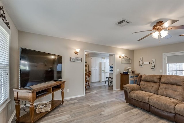 living area with ceiling fan, baseboards, light wood finished floors, and visible vents