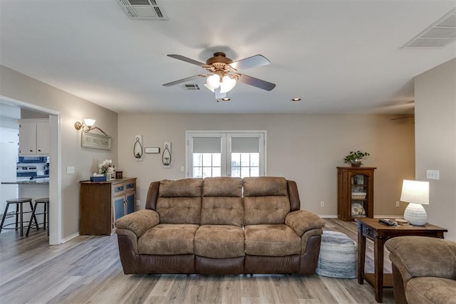 living area featuring light wood finished floors, a ceiling fan, and visible vents