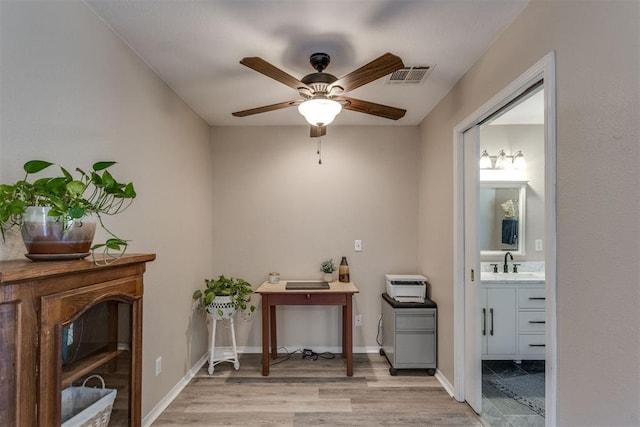 interior space featuring baseboards, a sink, visible vents, and light wood-type flooring