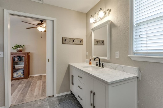 bathroom with baseboards, a ceiling fan, and vanity