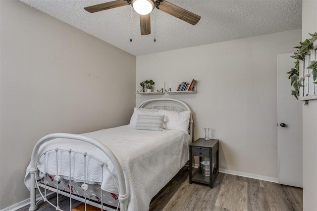 bedroom with wood finished floors, a textured ceiling, a ceiling fan, and baseboards