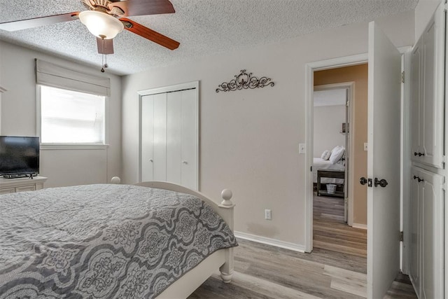 bedroom with a textured ceiling, a closet, light wood-style floors, ceiling fan, and baseboards