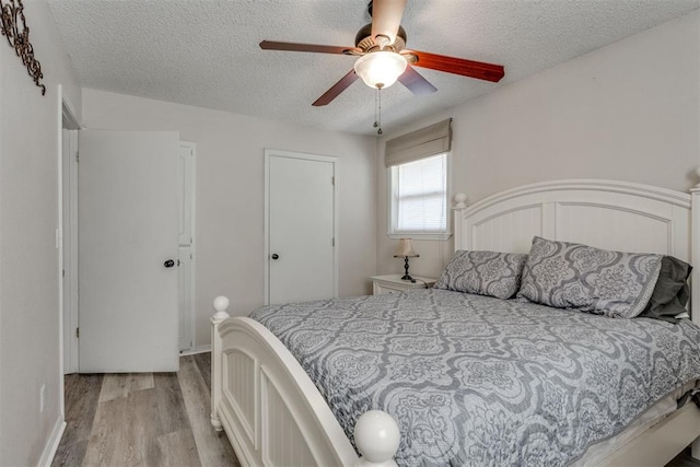 bedroom with light wood-type flooring, a ceiling fan, and a textured ceiling