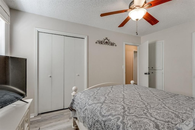 bedroom featuring a textured ceiling, a closet, light wood finished floors, and a ceiling fan
