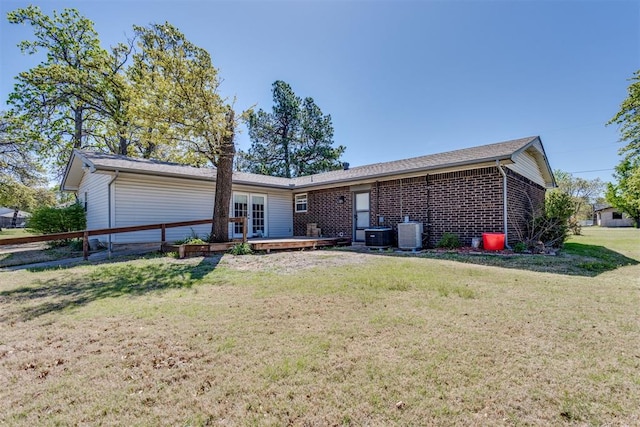 rear view of house featuring a wooden deck, a lawn, brick siding, and central AC unit