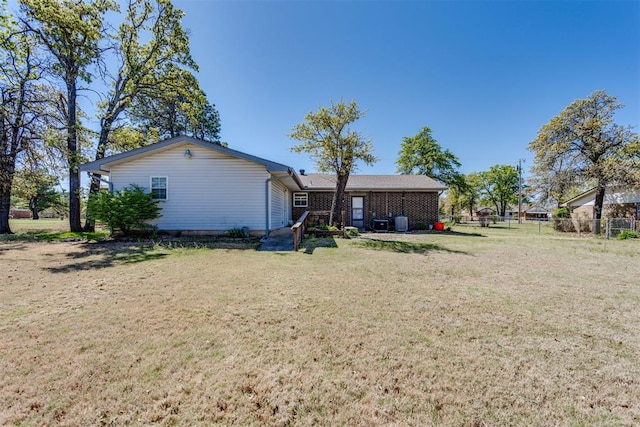 rear view of house with fence and a lawn
