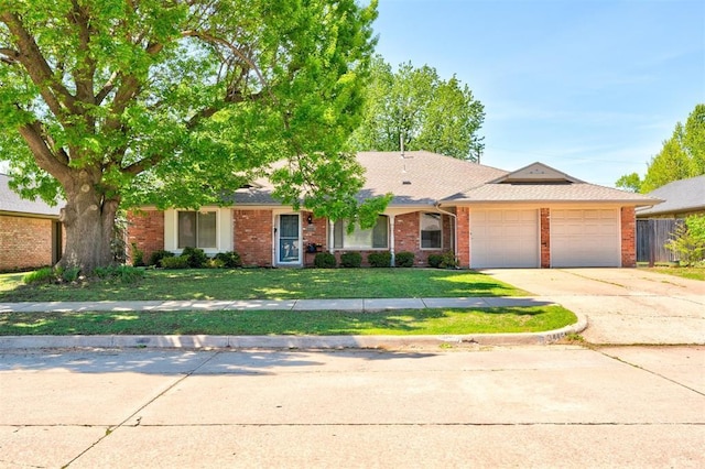 ranch-style house featuring concrete driveway, an attached garage, fence, brick siding, and a front lawn