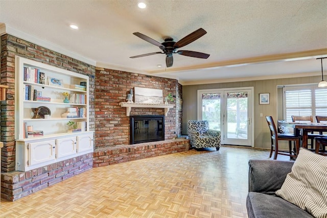 living area with recessed lighting, a brick fireplace, ceiling fan, crown molding, and a textured ceiling