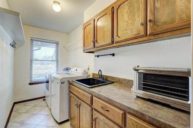 clothes washing area featuring a sink, washer and clothes dryer, light tile patterned floors, baseboards, and a toaster