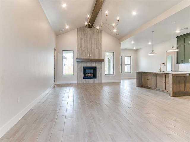 1715 Zayden Ln, Norman, OK 73072 - unfurnished living room with beamed ceiling, a fireplace, light wood finished floors, baseboards, and high vaulted ceiling