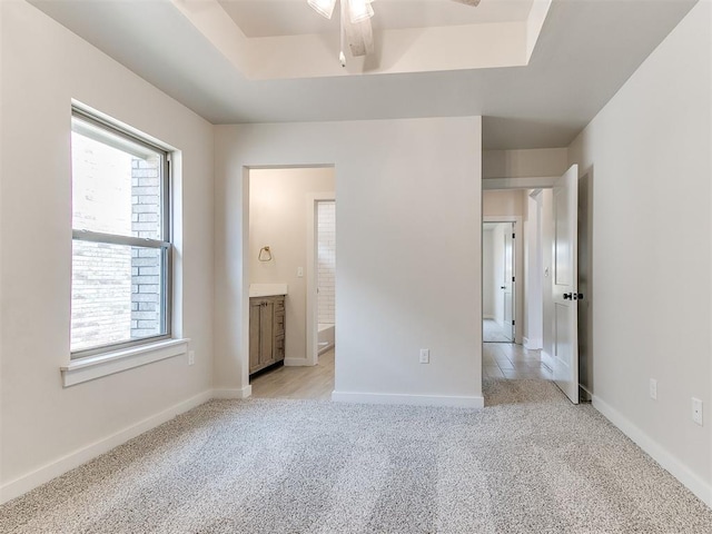 1715 Zayden Ln, Norman, OK 73072 - unfurnished bedroom featuring a raised ceiling, ensuite bathroom, baseboards, and light carpet