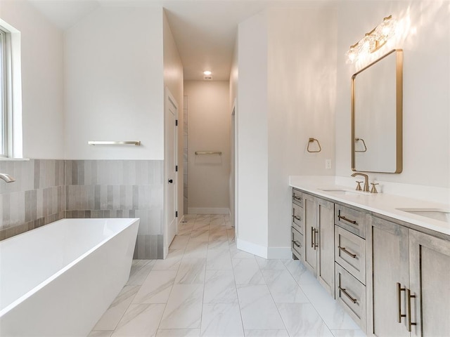 1715 Zayden Ln, Norman, OK 73072 - bathroom with a freestanding bath, double vanity, marble finish floor, a sink, and baseboards