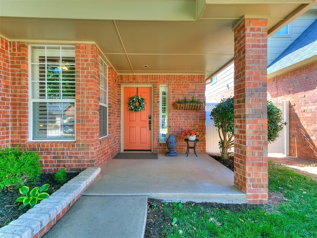 view of exterior entry featuring brick siding and a porch
