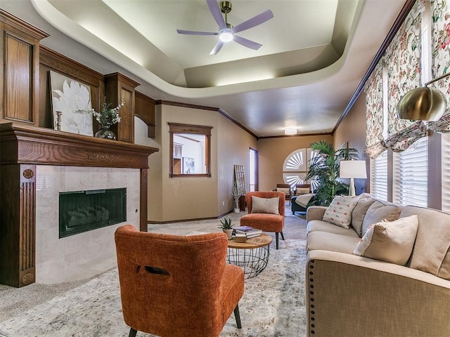 living area featuring crown molding, a ceiling fan, a fireplace, and a healthy amount of sunlight