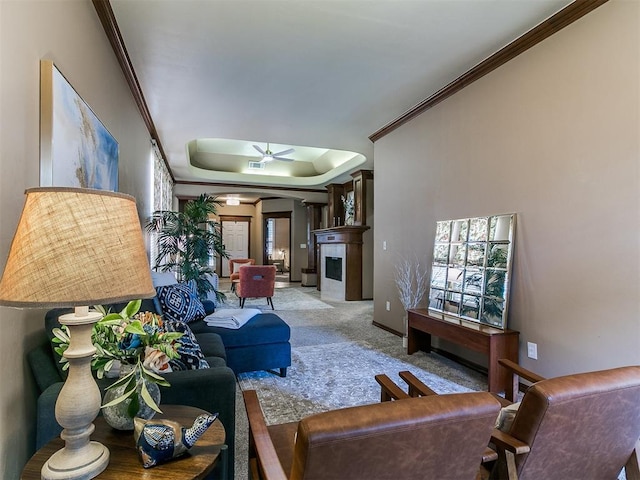carpeted living area featuring a fireplace with flush hearth, ceiling fan, arched walkways, and ornamental molding
