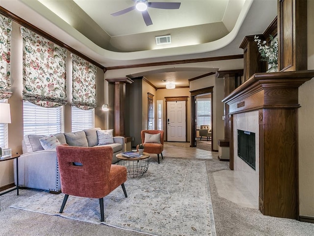 living room featuring crown molding, ceiling fan, a premium fireplace, baseboards, and visible vents