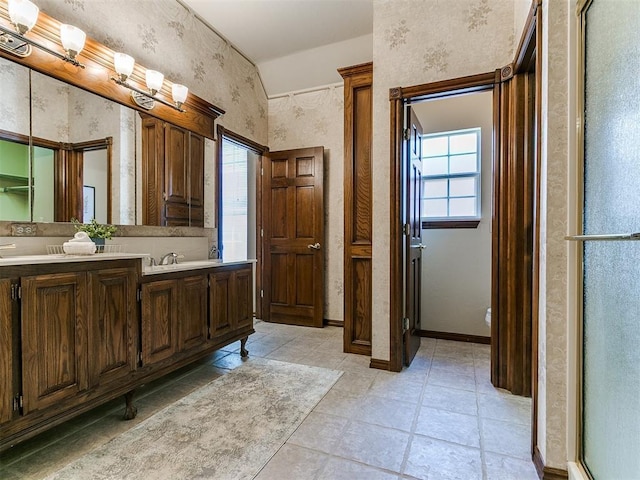 bathroom featuring tile patterned flooring, wallpapered walls, a sink, and double vanity