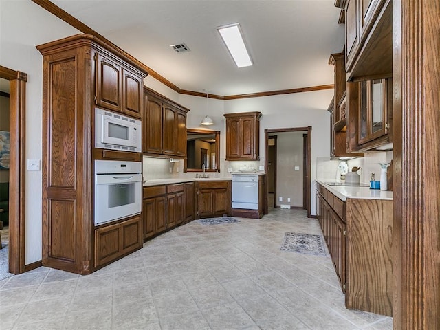 kitchen with light countertops, visible vents, a sink, white appliances, and crown molding