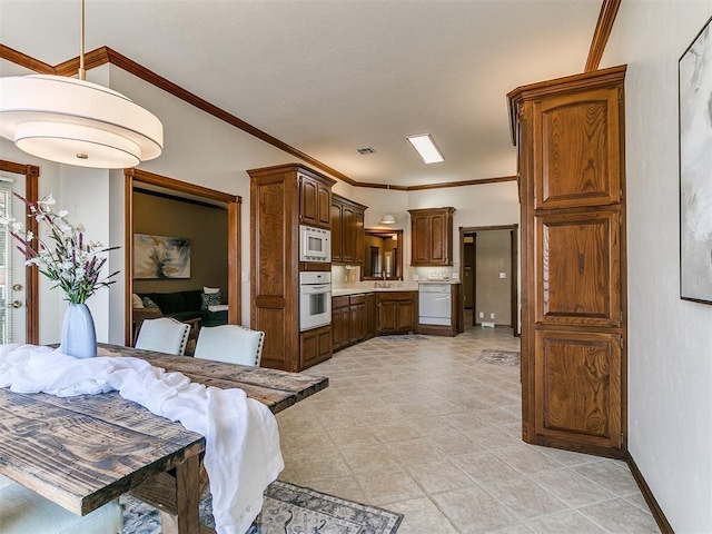 kitchen with baseboards, light countertops, white appliances, and ornamental molding