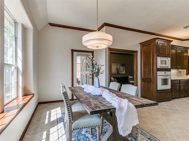 dining area featuring vaulted ceiling, a healthy amount of sunlight, ornamental molding, and light tile patterned floors
