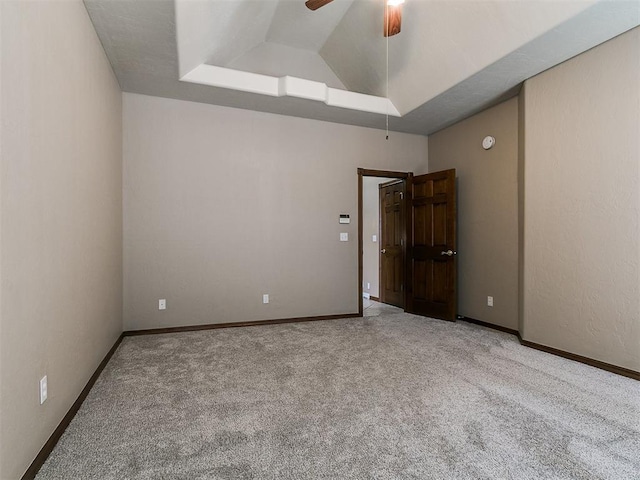 spare room with lofted ceiling, carpet flooring, baseboards, and a ceiling fan
