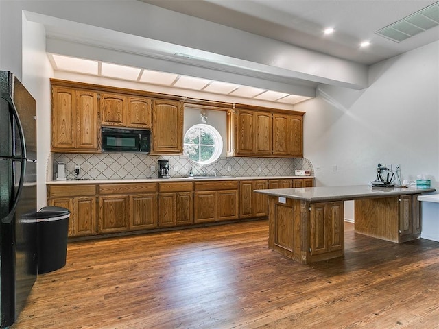 kitchen with visible vents, brown cabinets, black appliances, and tasteful backsplash