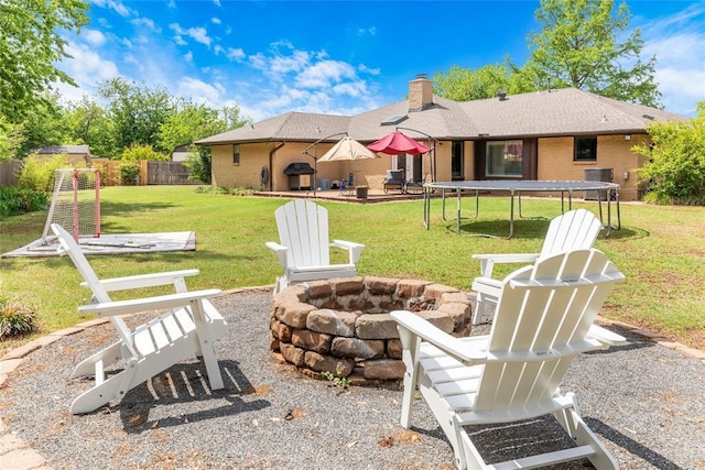 exterior space with a trampoline, a patio area, central air condition unit, fence, and a fire pit
