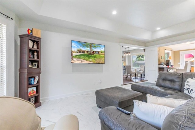 living room featuring recessed lighting, a tray ceiling, baseboards, and marble finish floor