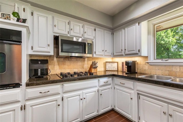 kitchen with white cabinets, stainless steel microwave, backsplash, and oven
