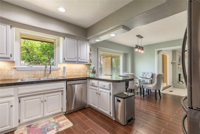 kitchen with a sink, a healthy amount of sunlight, dark countertops, and stainless steel appliances