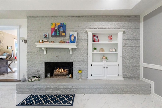 living area with marble finish floor, a brick fireplace, and built in shelves