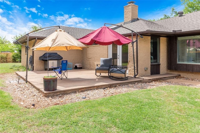 back of property with brick siding, a lawn, a chimney, and a deck
