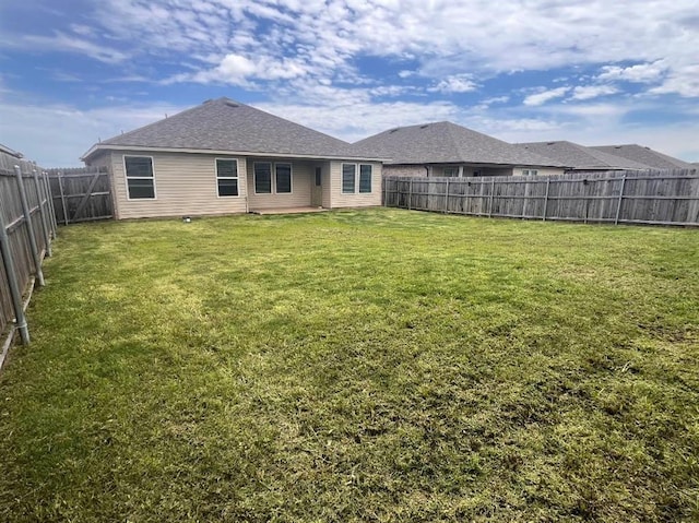 back of property with a lawn and a fenced backyard
