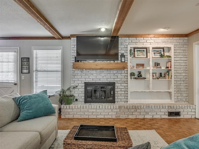 living area with a textured ceiling, a brick fireplace, and beamed ceiling