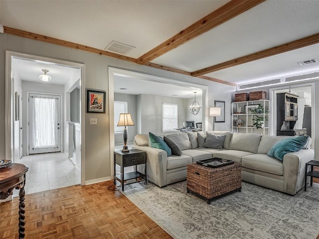 living area featuring beamed ceiling, visible vents, and a wealth of natural light