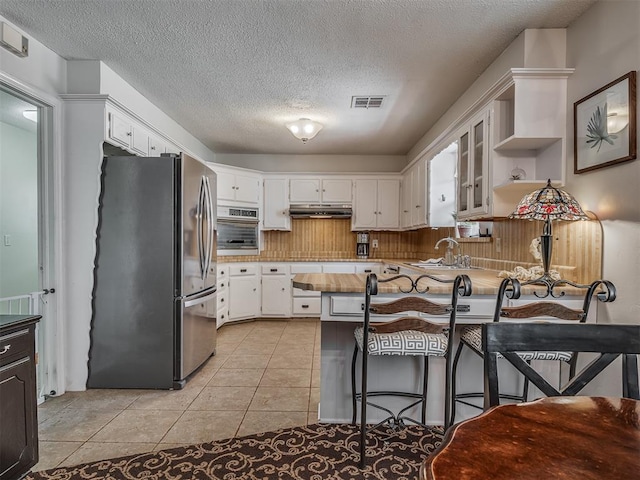 kitchen with visible vents, a peninsula, a textured ceiling, and appliances with stainless steel finishes