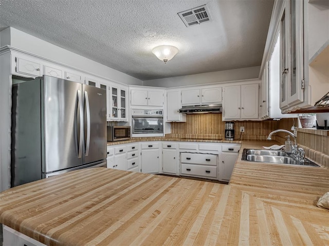 kitchen with visible vents, stainless steel appliances, a sink, under cabinet range hood, and white cabinetry