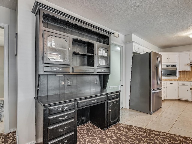 interior space with light tile patterned floors, appliances with stainless steel finishes, white cabinets, and a textured ceiling