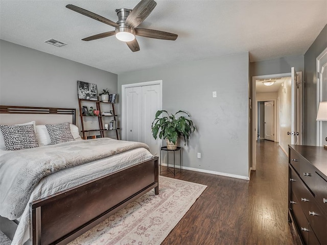 bedroom with ceiling fan, dark wood-style flooring, visible vents, baseboards, and a closet