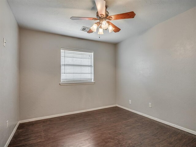 spare room featuring ceiling fan, baseboards, visible vents, and dark wood finished floors