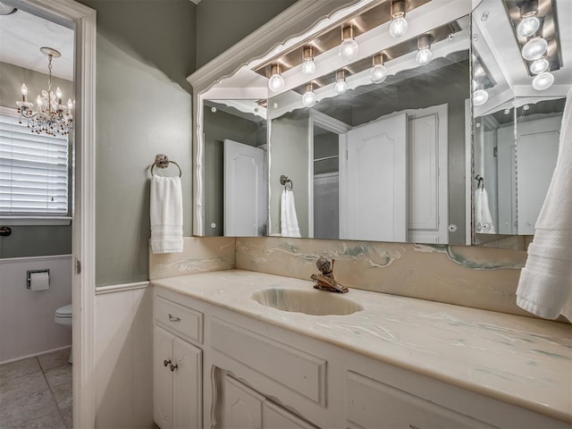 bathroom with vanity, wainscoting, toilet, tile patterned floors, and a chandelier