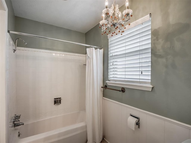 full bath featuring wainscoting, a notable chandelier, and shower / tub combo