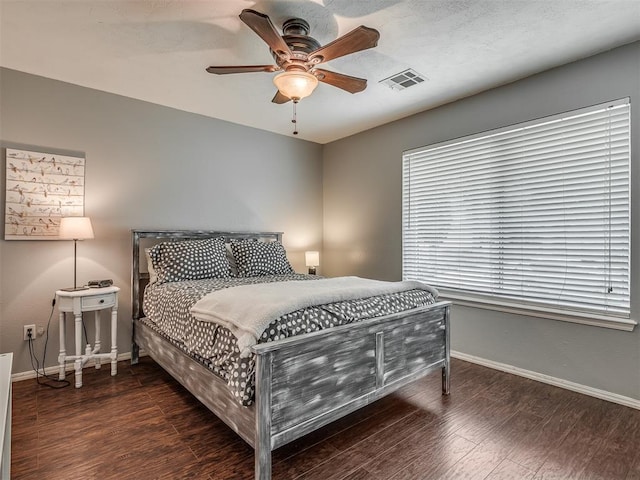 bedroom featuring visible vents, a ceiling fan, baseboards, and wood finished floors