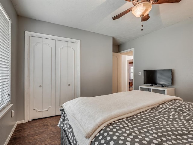 bedroom with a closet, baseboards, ceiling fan, and dark wood-type flooring