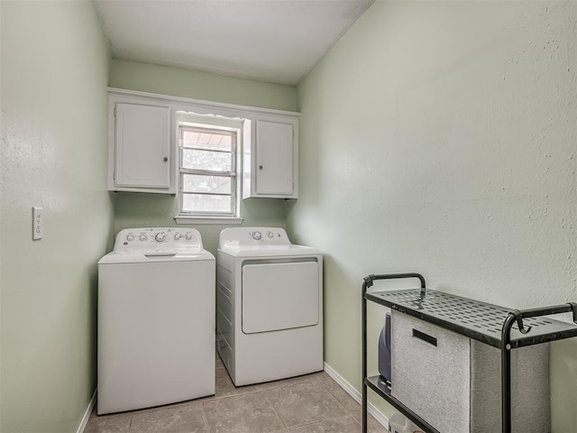 laundry room featuring light tile patterned floors, baseboards, cabinet space, and washing machine and clothes dryer